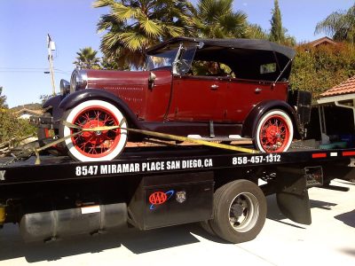 red vintage car on tow truck